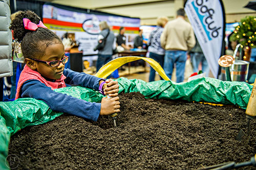 Mona Taylor plays in a big bag of dirt during the North Atlanta Home Show at the Infinite Energy Center in Duluth on Saturday, February 20, 2016.