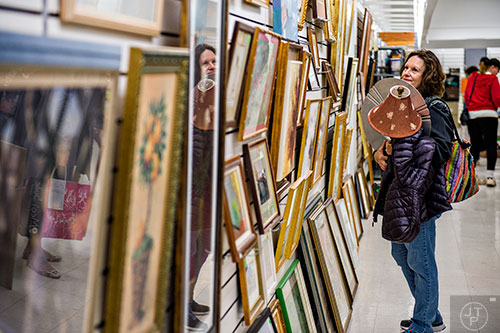 Dena Amoth carries an armfull of items as she looks at paintings during the 25th annual Sandy Springs Society Tossed Out Treasures sale at Marshall's Plaza in Sandy Springs on Saturday, February 27, 2016. 