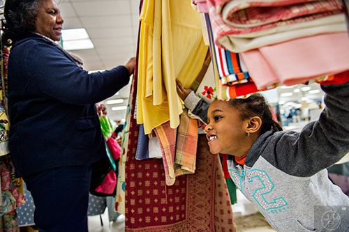 Kaylen Swain (right) plays a game with her grandmother Gwenn as she looks at tablecloths during the 25th annual Sandy Springs Society Tossed Out Treasures sale at Marshall's Plaza in Sandy Springs on Saturday, February 27, 2016. 