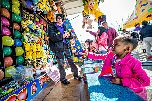 Londyn Harshaw (right) tries to pop a balloon as she throws a dart at the Atlanta Fair near Turner Field in downtown on Saturday, February 27, 2016. 