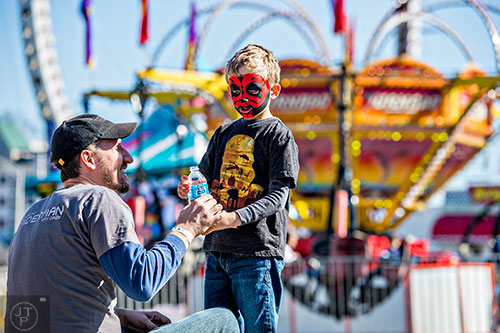 Chase Deren (right) takes a short water break with his father Eric before getting on another ride at the Atlanta Fair near Turner Field in downtown on Saturday, February 27, 2016. 
