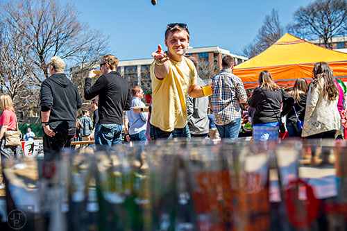 Jordan Avery (center) tries to toss a bottle cap into a beer glass during the Atlanta Brunch Festival at Fourth Ward Park in Atlanta on Saturday, March 5, 2016. 