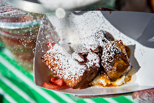 The guys at Dish Dive add powdered sugar to their pork belly and French toast with grits offering during the Atlanta Brunch Festival at Fourth Ward Park in Atlanta on Saturday, March 5, 2016.