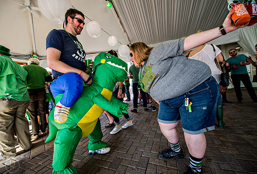 A woman bends down to kiss Will Rowe's dinosaur during LepreCon at Park Tavern in Atlanta on Saturday, March 5, 2016. 