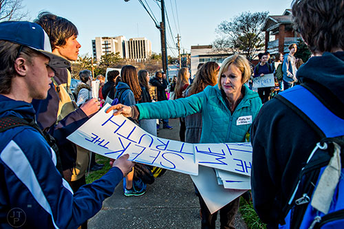 Bailey Pendergrast (center) hands out signs to people in the crowd gathered across from Decatur High School during the Rally for Riley on Monday morning.