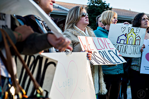 Caroline Grimes (center) holds a sign in support of Susan Riley during the Rally for Riley across from Decatur High School on Monday morning.