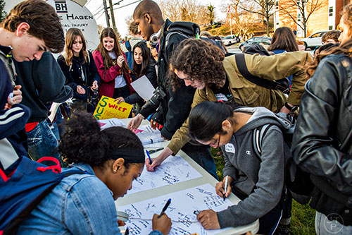 Supporters of Susan Riley crowd around a table to write her letters during the Rally for Riley across from Decatur High School on Monday morning.