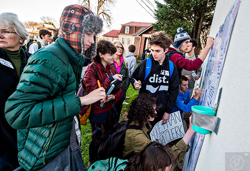 Supporters of Susan Riley write notes on a sign during the Rally for Riley across from Decatur High School on Monday morning.