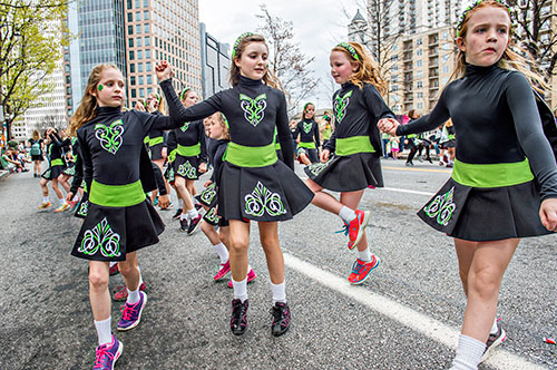 Jenevieve Lapierre (left) and Aisoing Mahony dance their way down Peachtree St. during the annual Atlanta St. Patrick's Day Parade on Saturday, March 12, 2016. 