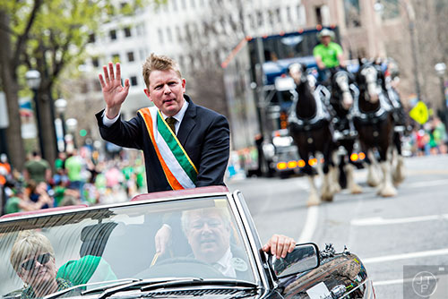 Consul General of Ireland Shane Stephens (left) waves to the crowd as he rides down Peachtree St. during the annual Atlanta St. Patrick's Day Parade on Saturday, March 12, 2016. 