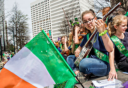 Lily Garcia (right) plays music as she rides a float down Peachtree St. during the annual Atlanta St. Patrick's Day Parade on Saturday, March 12, 2016. 