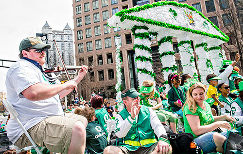 Wes Macky (left) plays the fiddle as he rides a float down Peachtree St. during the annual Atlanta St. Patrick's Day Parade on Saturday, March 12, 2016. 