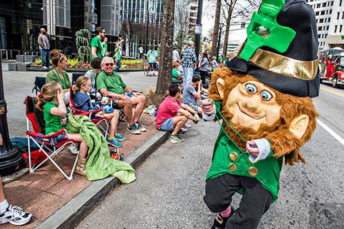 Dressed as a leprechaun, Rob Stephens passes out beads as he marches down Peachtree St. during the annual Atlanta St. Patrick's Day Parade on Saturday, March 12, 2016. 