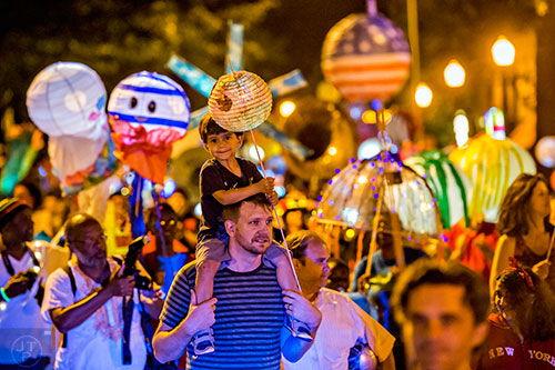 Nyle Corey (center) rides on his father Alan's shoulders during the third annual lantern parade on Friday.