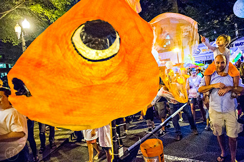 Brian Logan (right) carries his daughter Drew on his shoulders as they enter Decatur Square during the third annual lantern parade on Friday.