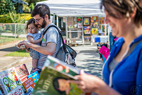 Mathew George buys a book for his daughter Lillian during the Kirkwood Spring Fling on Saturday.