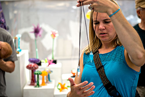 Julie Schuman looks at glass pendants during the Decatur Arts Festival on Saturday.