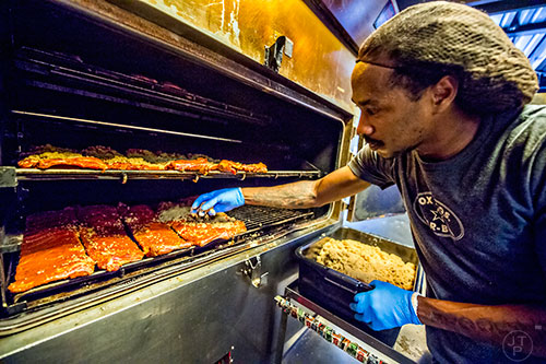 Putting the finishing touches, i.e. brown sugar, on a smoker filled with ribs in the smoke room at Fox Bros. Barbecue off of Dekalb Ave. in Atlanta.