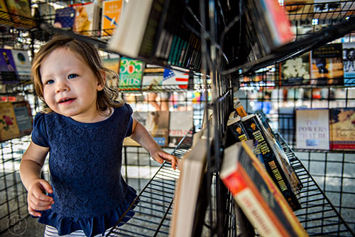 Sabina Uroic plays amongst racks of books during the Decatur Book Festival on Saturday.
