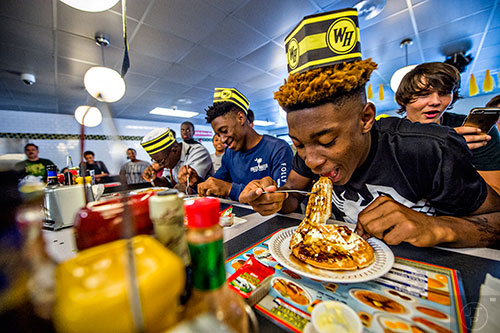 Demetrius Hicks (right) shoves a quarter waffle into his mouth as the waffle eating contest gets underway at the Waffle House off of Decatur Square on Friday.