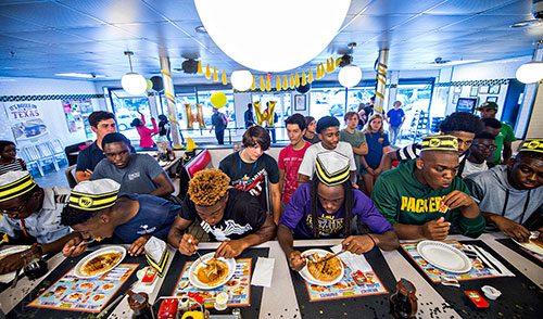Six contestants participate in the first round of the waffle eating contest at the Waffle House off of Decatur Square on Friday.