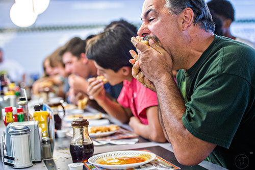 Steve Schultz (right) shoves a whole waffle into his mouth to gain an early lead during the waffle eating contest at the Waffle House in Decatur on Friday.