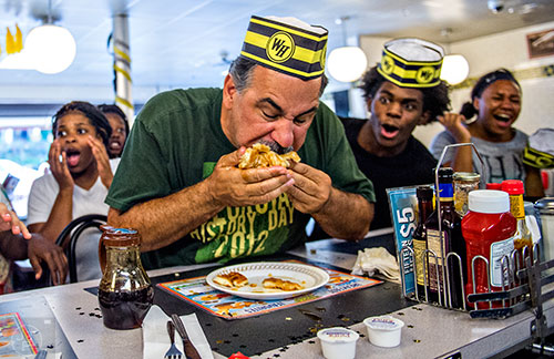 Steve Schultz (center) shoves a whole waffle into his mouth as he tries to make a move to take over the lead during the championship round of the waffle eating contest at the Waffle House in Decatur on Friday.