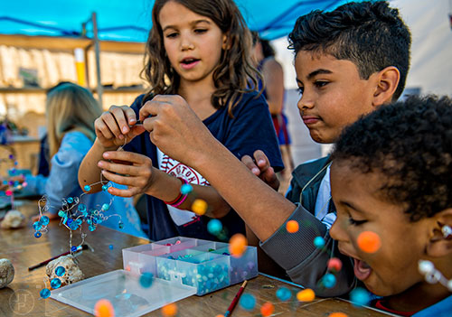 Sienna Ampola (left) and Esteban Guzman work on a bead project as Nicolas Guzman watches during the Atlanta Maker Faire in Decatur on Saturday.