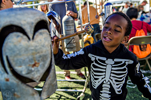 Bryson Powell tries his hand at making music while banging on handmade bells during the Atlanta Maker Faire in Decatur on Saturday.