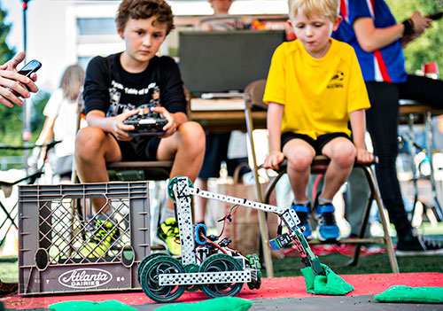 A robot under the control of Jackson Armstrong (left) picks up a beanbag as Owen Burke waits his turn during the Atlanta Maker Faire in Decatur on Saturday.