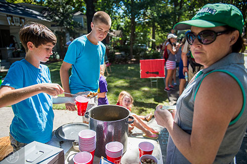 Sean Wiseman (left) and Connor Ramming scoop boiled peanuts into a cup for Lisa Chader during the annual Oakhurst PorchFest on Saturday.