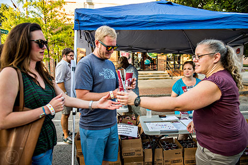 Alex Peister (right) hands out glasses and passports to Scott Jones and Sarah Fitzgerald during the Kirkwood Wine Stroll on Friday.