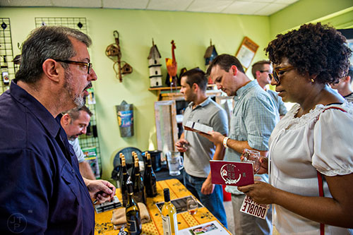 Holly Reid (right) talks with Tom Trainor inside Kirkwood Seed & Feed as he pours wine during the Kirkwood Wine Stroll on Friday.