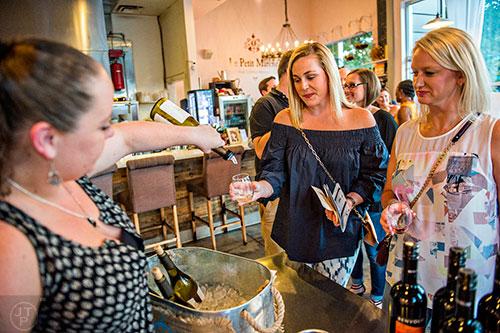 Laura Weatherford (right) and Elizabeth Campbell hold out their glasses as Savannah Kirkwood fills them with wine at Le Petite Manche during the annual Kirkwood Wine Stroll on Friday.