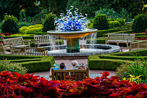 A couple looks at their map as they sit on a bench near Mershon Hall at the Atlanta Botanical Garden during Chihuly in the Garden.