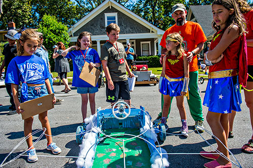 Lola DiCarlo (left), Audrey Trujillo and Wiliiam Roach judge the Team Hall Netherton car as Josh Netherton and his daughters Elizabeth and Penny tak about how they came up with the Wonder Woman theme before the start of the 6th annual Madison Ave. Soapbox Derby in Oakhurst on Saturday.