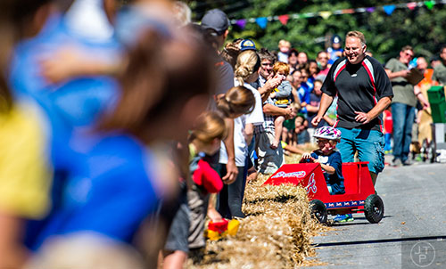 Chased by her father, Blythe Hart crashes into the hay bales during the 6th annual Madison Ave. Soapbox Derby in Oakhurst on Saturday.