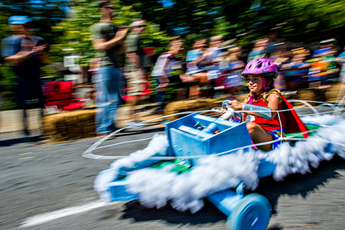 Dressed as Wonder Woman, Penny Netherton steers her invisible jet racer down the street during the 6th annual Madison Ave. Soapbox Derby in Oakhurst on Saturday.