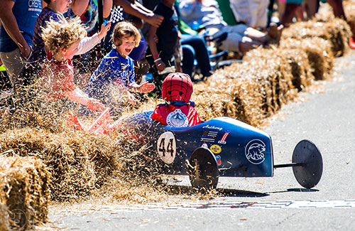 Anthony Amelio crashes into hay bales as he crosses the finish line during the 6th annual Madison Avenue Soapbox Derby on Saturday.