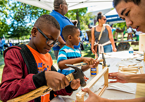 Richmond Doomah (left) and Charles Pierson help Anthony Nguyen build slats for Georgia Tech's urban beehive project during the Atlanta Maker Faire in Decatur on Saturday.