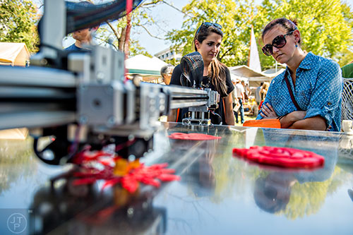 Alison Hight (right) and Emily Fitzharris watch as a 3D printer cuts a snowflake during the Atlanta Maker Faire in Decatur on Saturday.
